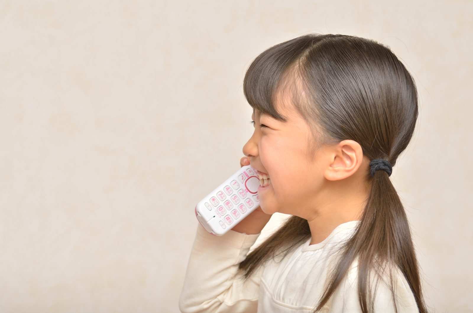 A young girl laughing while talking on the family's cordless home phone